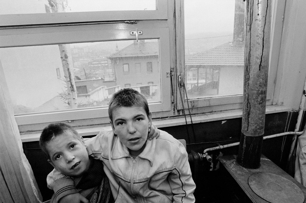Two children huddle for warmth and comfort by the stove at the Home For Mentally Handicapped Children. Because of shortage of fuel, this room is the only one which is heated in the whole of the building. Sarajevo. 1993.