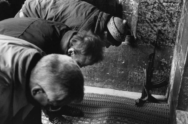 A Bosnian policeman has put his Kalashnikov gun in front of him during Friday prayer at the Gazi Husref Begova Mosque in Sarajevo. 1993.