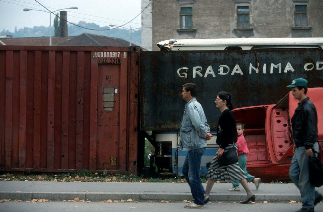 Pedestrians on Sniper Alley back road, protected by cars and containers walls from the snipers shots. Sarajevo, October 1993. © Alexandra Boulat / Association Pierre & Alexandra Boulat