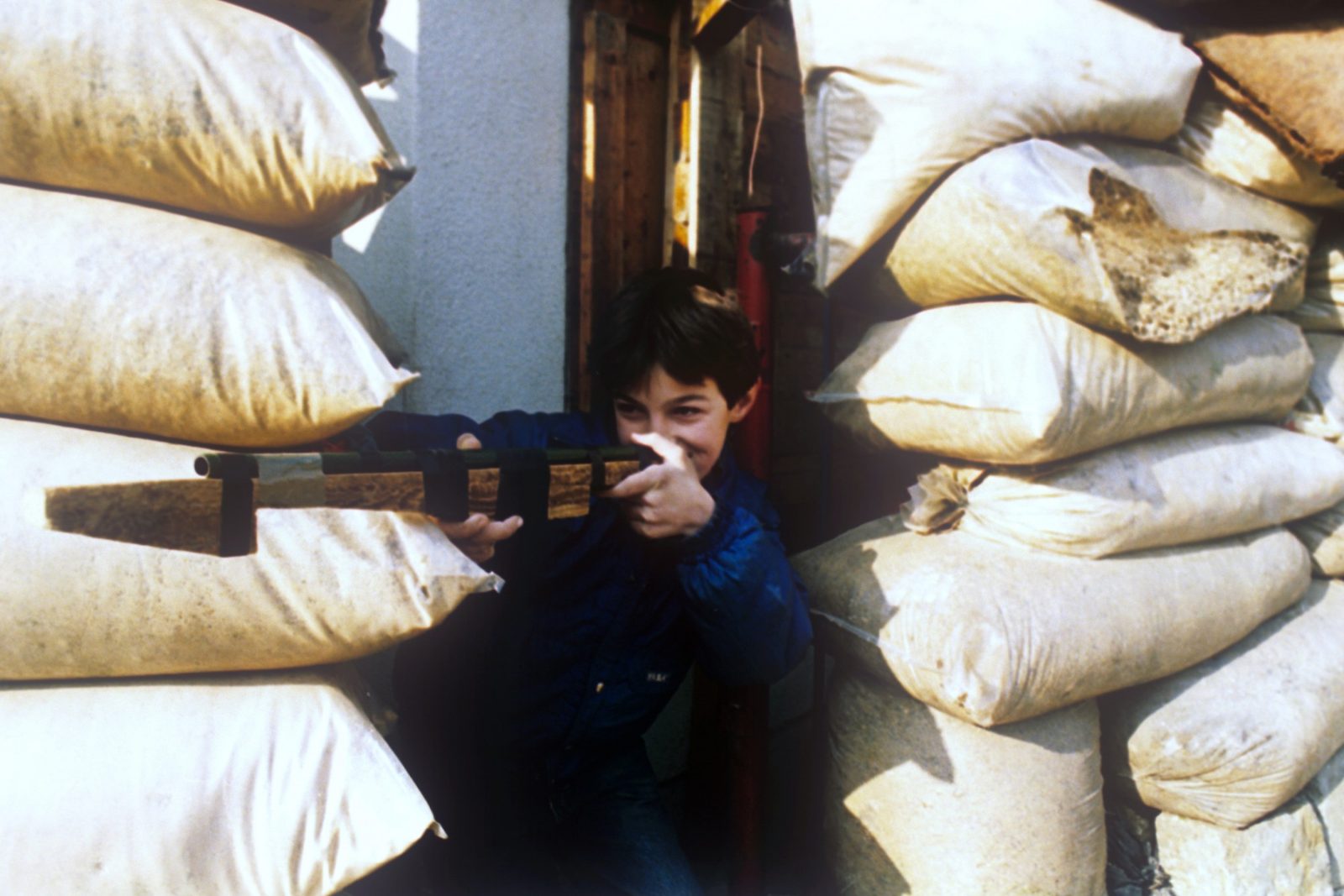 A boy plays war game at the sandbag wall in Sarajevo, Bosnia And Herzegovina, 18 January 1993. EPA/ANJA NIEDRINGHAUS