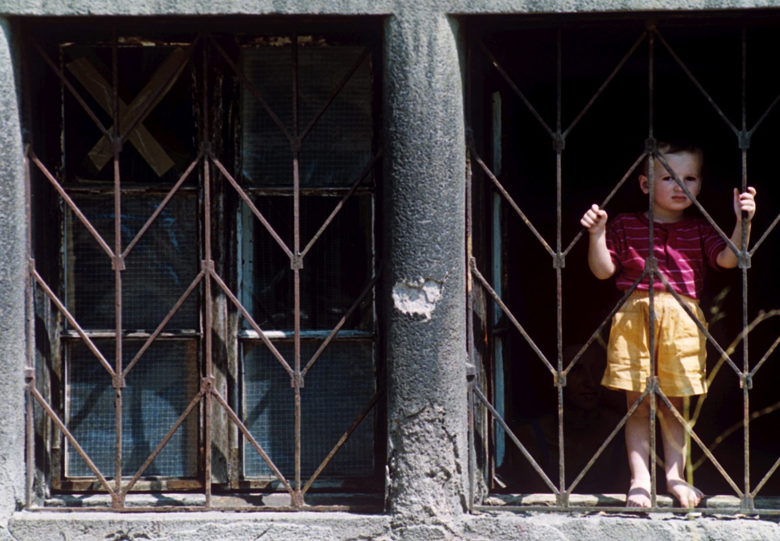 A Bosnian girl looks out of the window of the damaged building in Sarajevo, Bosnia And Herzegovina, 23 July 1995. EPA/ANJA NIEDRINGHAUS