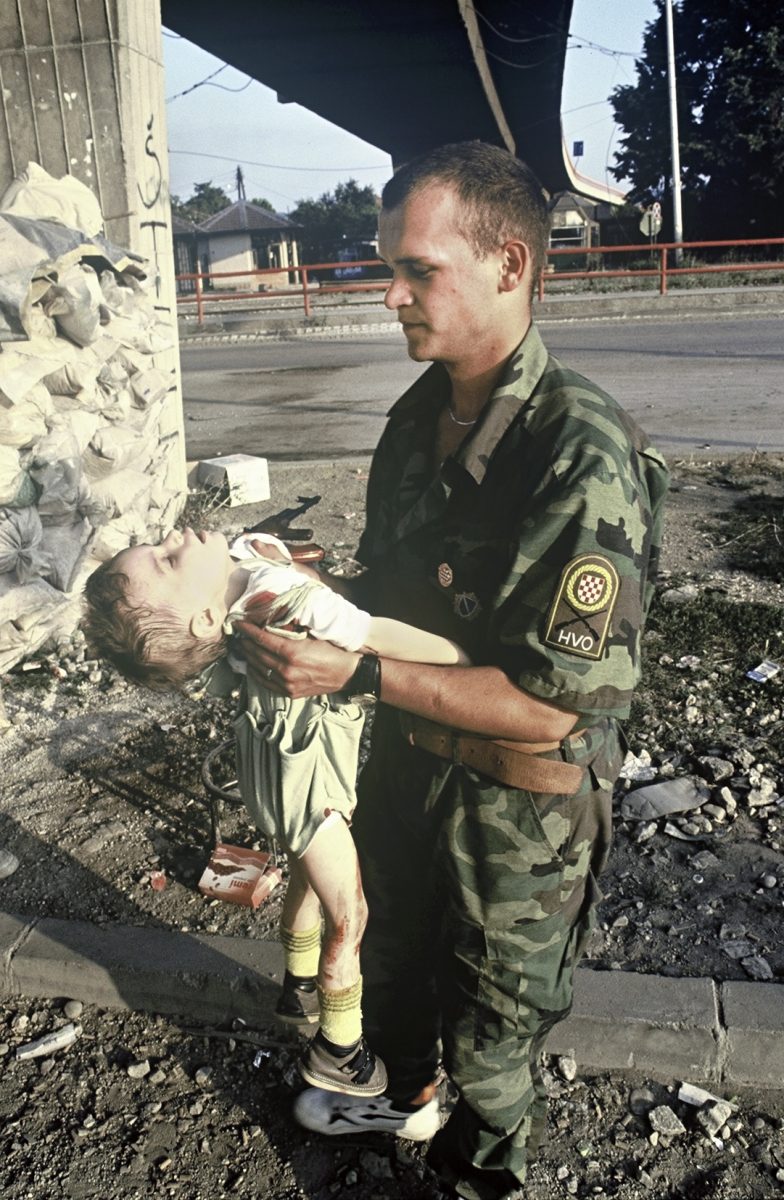 HVO soldier holds Vedrana Glavas (2 years old), who was badly wounded by the attack. A little later she passed away in his arms. Bosnia and Herzegovina, Sarajevo 01.08.1992