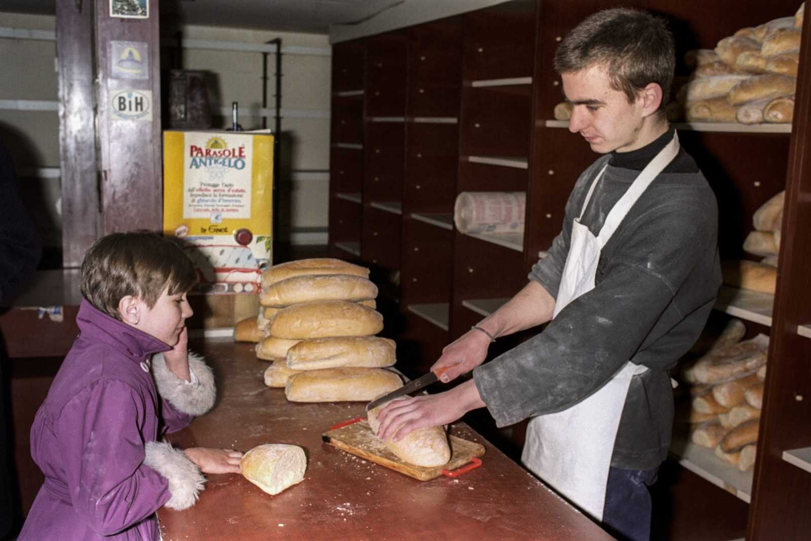 A child watches his daily ration of bread being sliced, Sarajevo, 1 December 1992. Starting 1 December each person will only be allowed to buy 233 grams of bread. EPA | DIMITRI MESSINIS