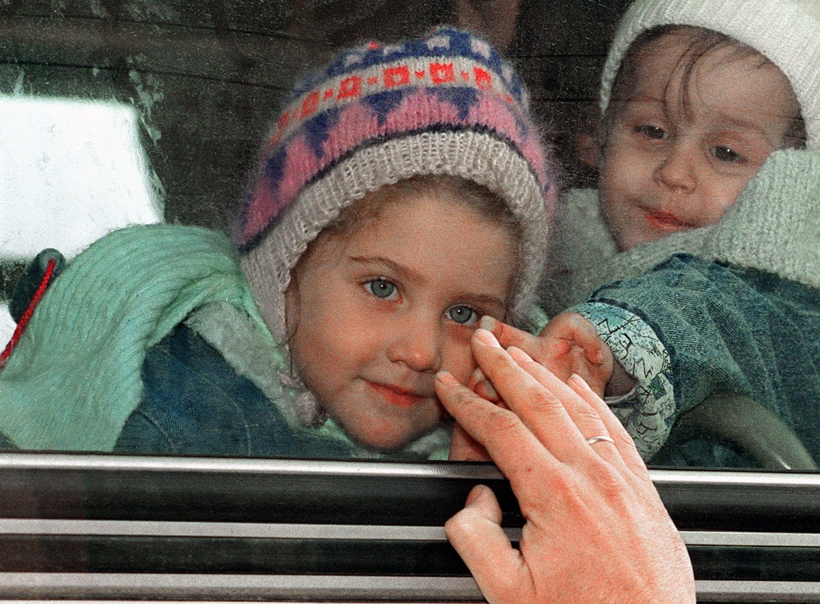 Bosnian child tries to reach her father's hand through a coach window before being evacuated from the besieged city of Sarajevo, 17 December 1992. More than 700 other refugees, most of them women, children and elderly people, were fleeing the war-stricken capital for shelter in Belgrade. EPA | DIMITRI MESSINIS