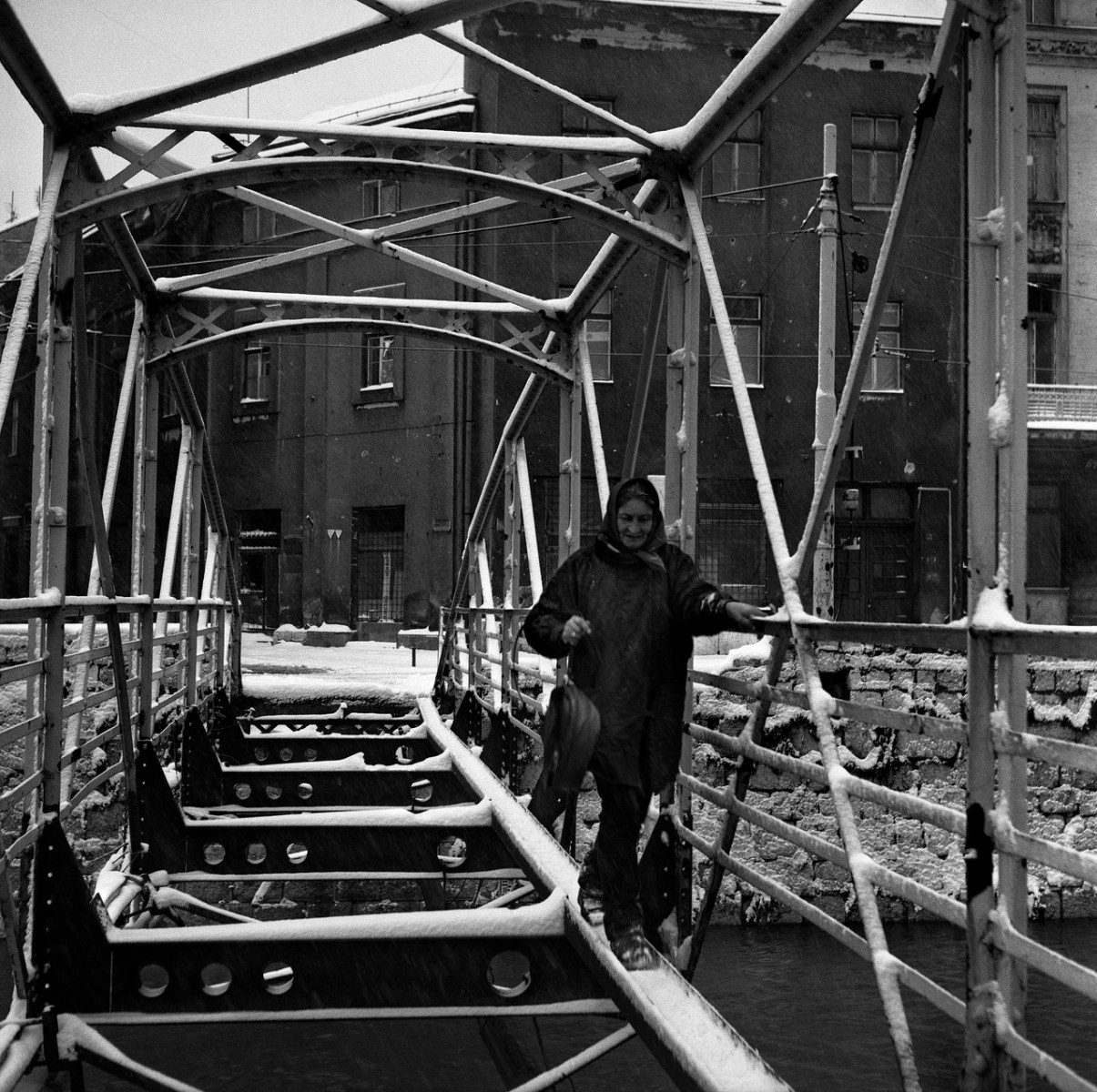 1994,Bosnia-Herzegovina ; Sarajevo : A civilian navigates the Cumurija footbridge that spans the Milijacka river in the center of Sarajevo.The wooden base was removed by civilians to heat their homes.