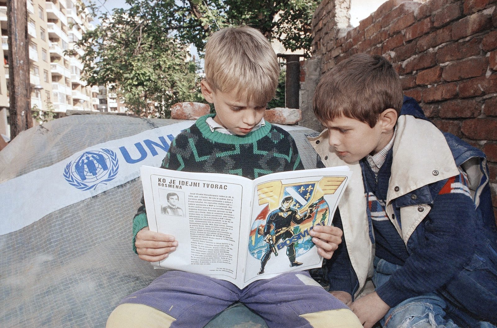 Two children read the first issue of the comic book called Bosman in a street in downtown Sarajevo, on Wednesday, 19 October 1994. The title character is a young Superman look-alike who becomes a superhero ready to defend his city from the besieging Serb army.
