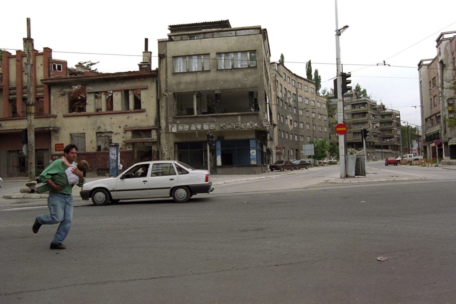 A father runs carrying his child across Sniper Alley as sniper fire breaks out in Sarajevo, Bosnia and Hercegovina, 06 June 1995.