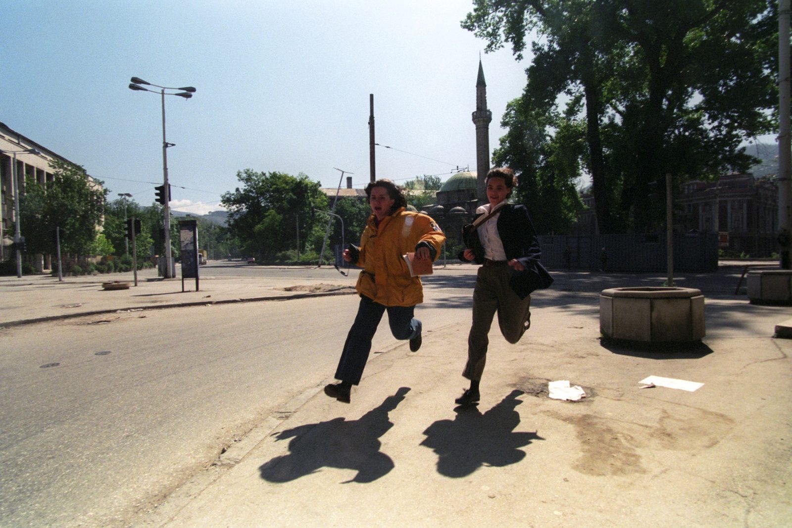 Two women chasing their shadows as they flee from sniper fire in the city centre in Sarajevo, Bosnia and Hercegovina, 24 May 1995.