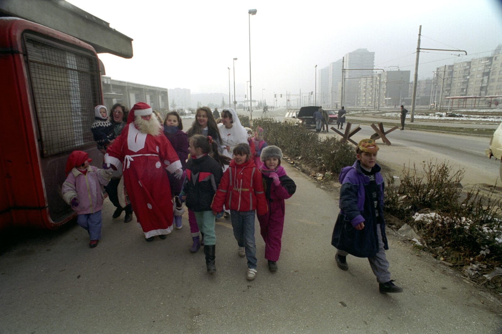 A Father Christmas figure accompanies young children on a stroll through the city streets in Sarajevo, Bosnia and Hercegovina, 31 December 1993.