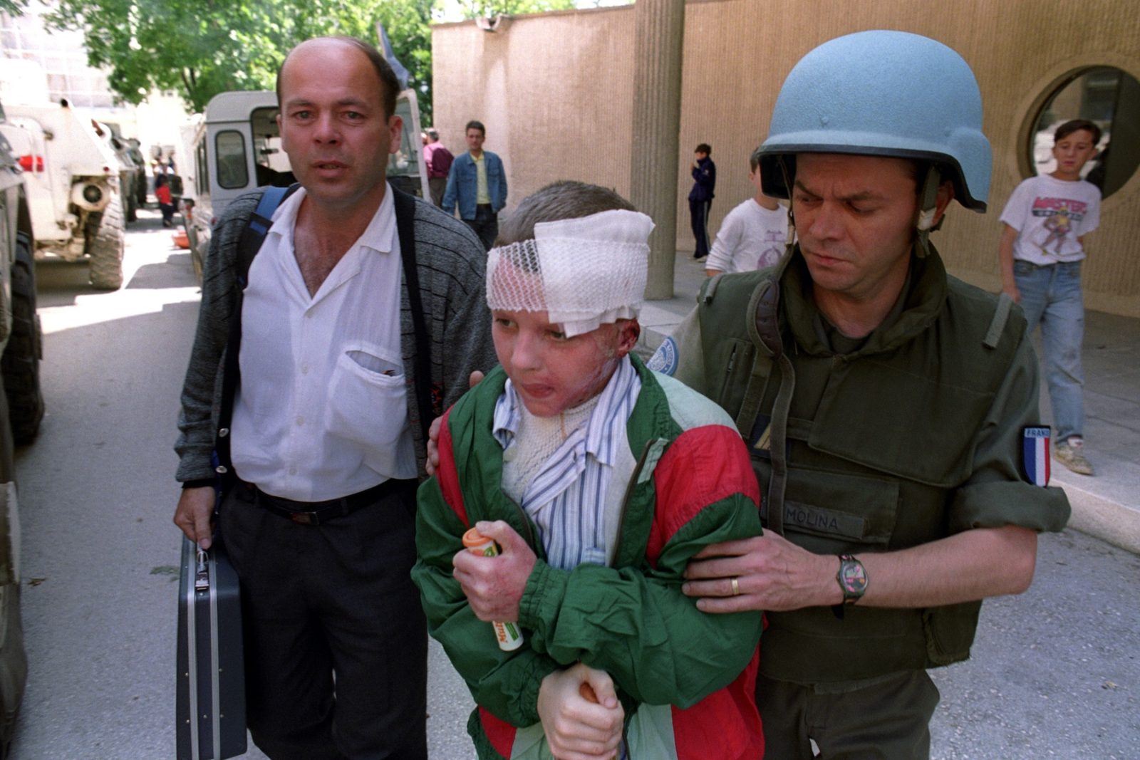 A young boy with a head wound following sniper fire is assisted by a French UN soldier as he makes his way to hospital in Sarajevo, Bosnia and Hercegovina, 29 June 1993.