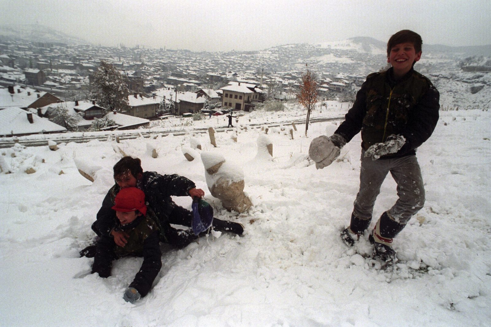 Youngsters frolic in the thick snow high above the city following heavy overnight snowfall in Sarajevo, Bosnia and Hercegovina, 16 November 1993.