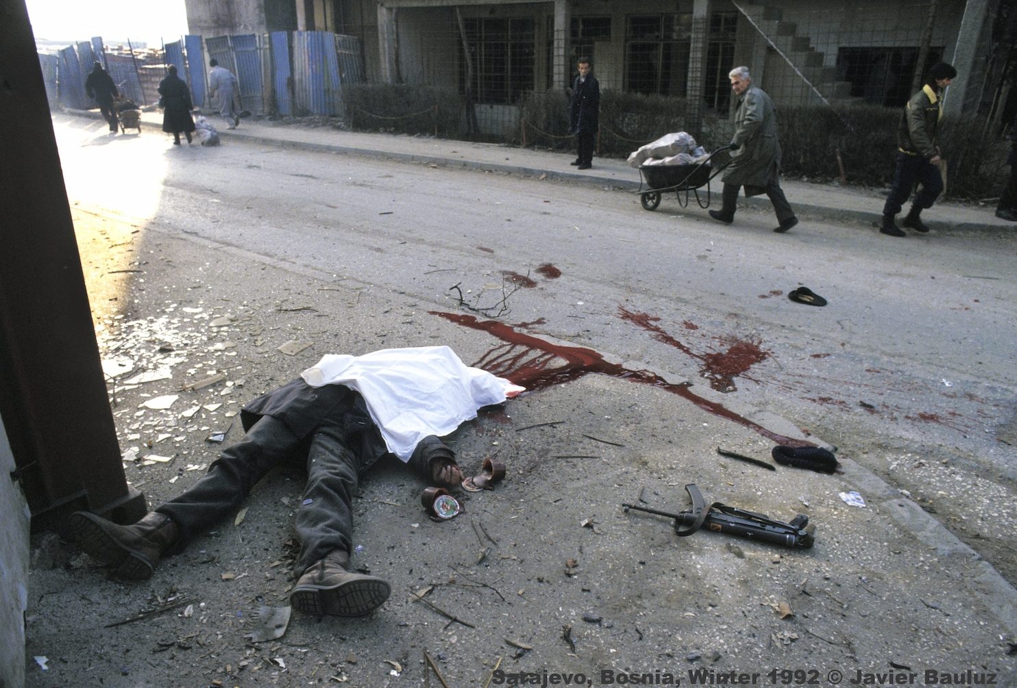 Sarajevo citizens run with firewood and water after Serb attack that killed a Bosnian policeman while eating yogurt in downtown Sarajevo. Sarajevo Bosnia and Herzegovina, Winter 1992.