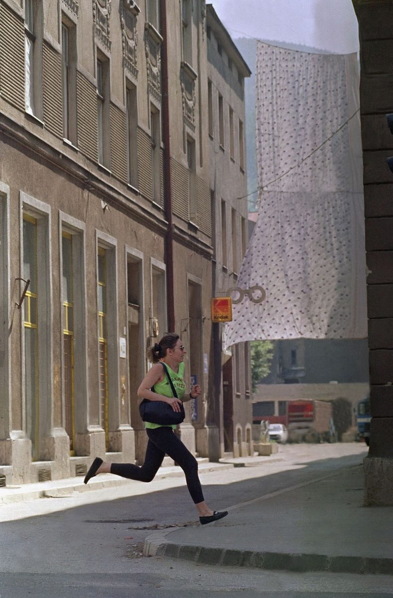 Woman crosses a sniper area in a hurry which is protected by sheets on in Sarajevo. People in the besieged Bosnian capital are still afraid of sniper attacks on their way through the city. Sarajevo 1992