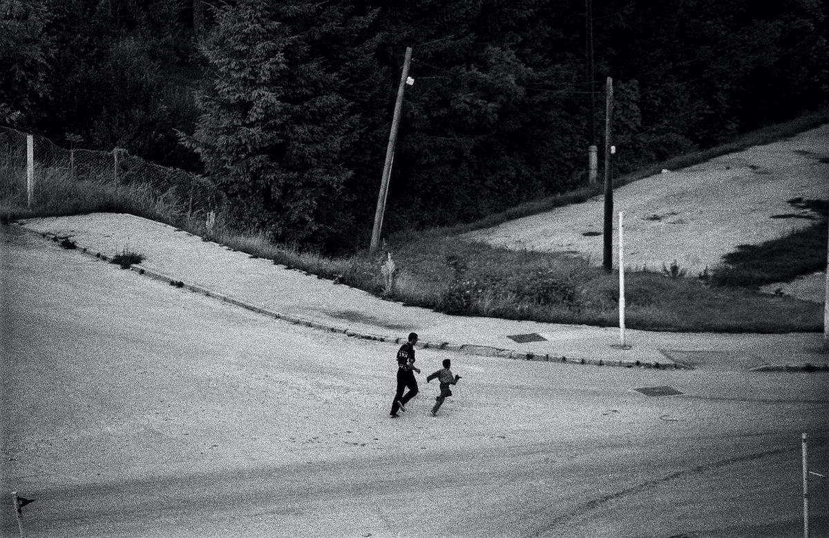 A boy runs with his father during an bomb alarm in the streets of Sarajevo. Sarajevo, Bosnia and Herzegovina, July 1995