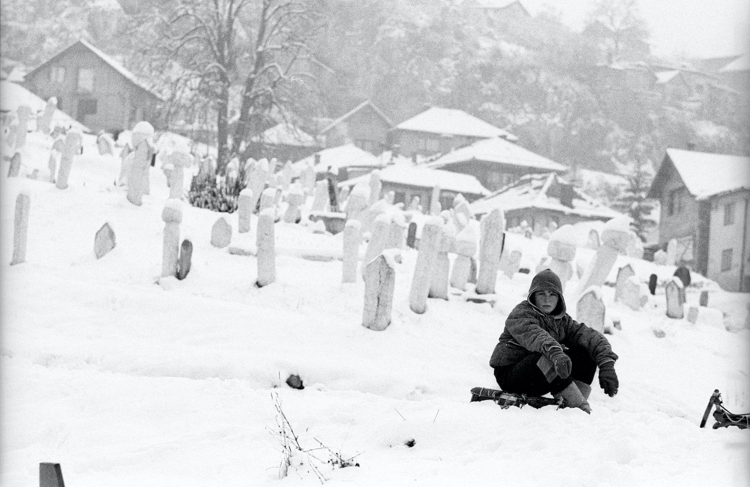 A boy on his sled in a graveyard on the first hill of Sarajevo. Sarajevo, Bosnia and Herzegovina, December 1994