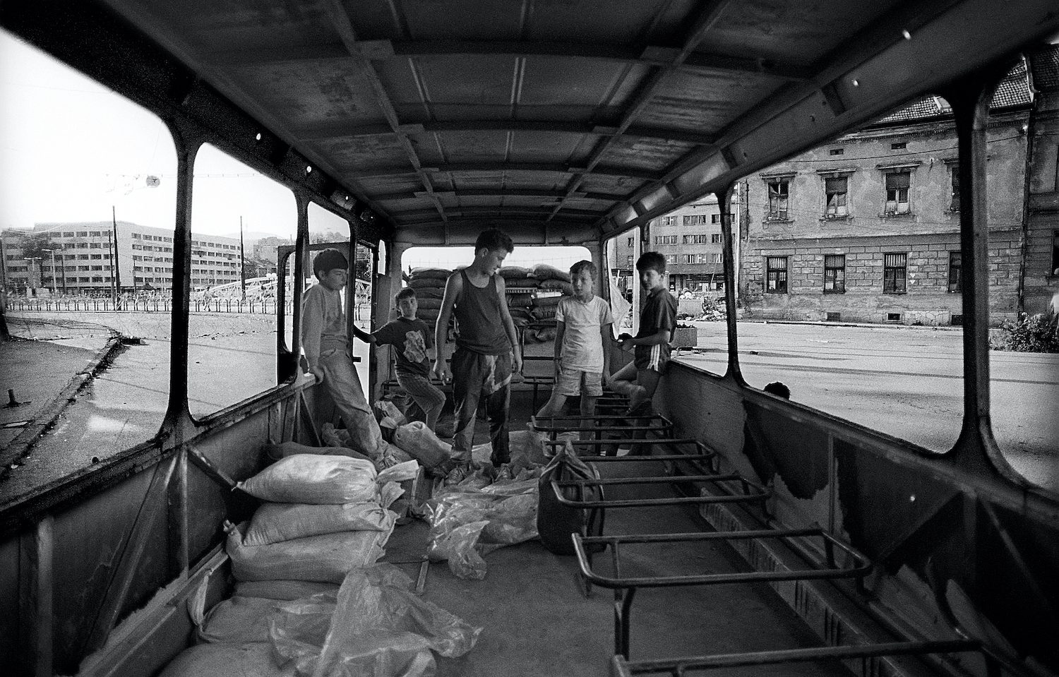Some guys playing inside a destroyed bus close to the front line in the centre of Sarajevo. Sarajevo, Bosnia and Herzegovina, August 1993