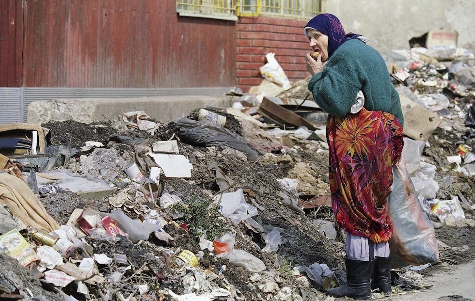 A Sarajevo woman eats a bit of food she found in a pile of trash on the street, April 6, 1993 in Sarajevo. Even though the United Nations airlift of food has resumed as well as the ground convoys of food into the Bosnian capital, after one year of siege, many Sarajevans still have to scavange for food to survive. After a year of war in Sarajevo, peace in Bosnia seems as remote as ever. (AP Photo/Michael Stravato)