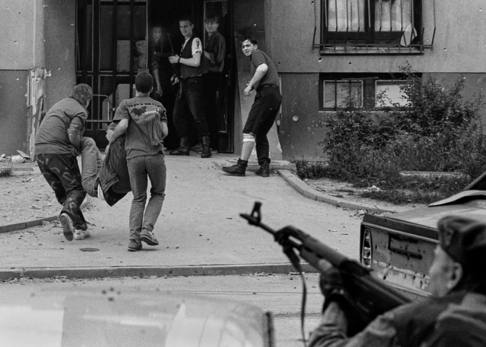 A wounded Bosnian ambulance driver is carried into a building in Sarajevo's Dobrinja suburb by Bosnian government fighters on June 24, 1992. He was driving one of three ambulances that came under fire from Bosnian Serb positions.