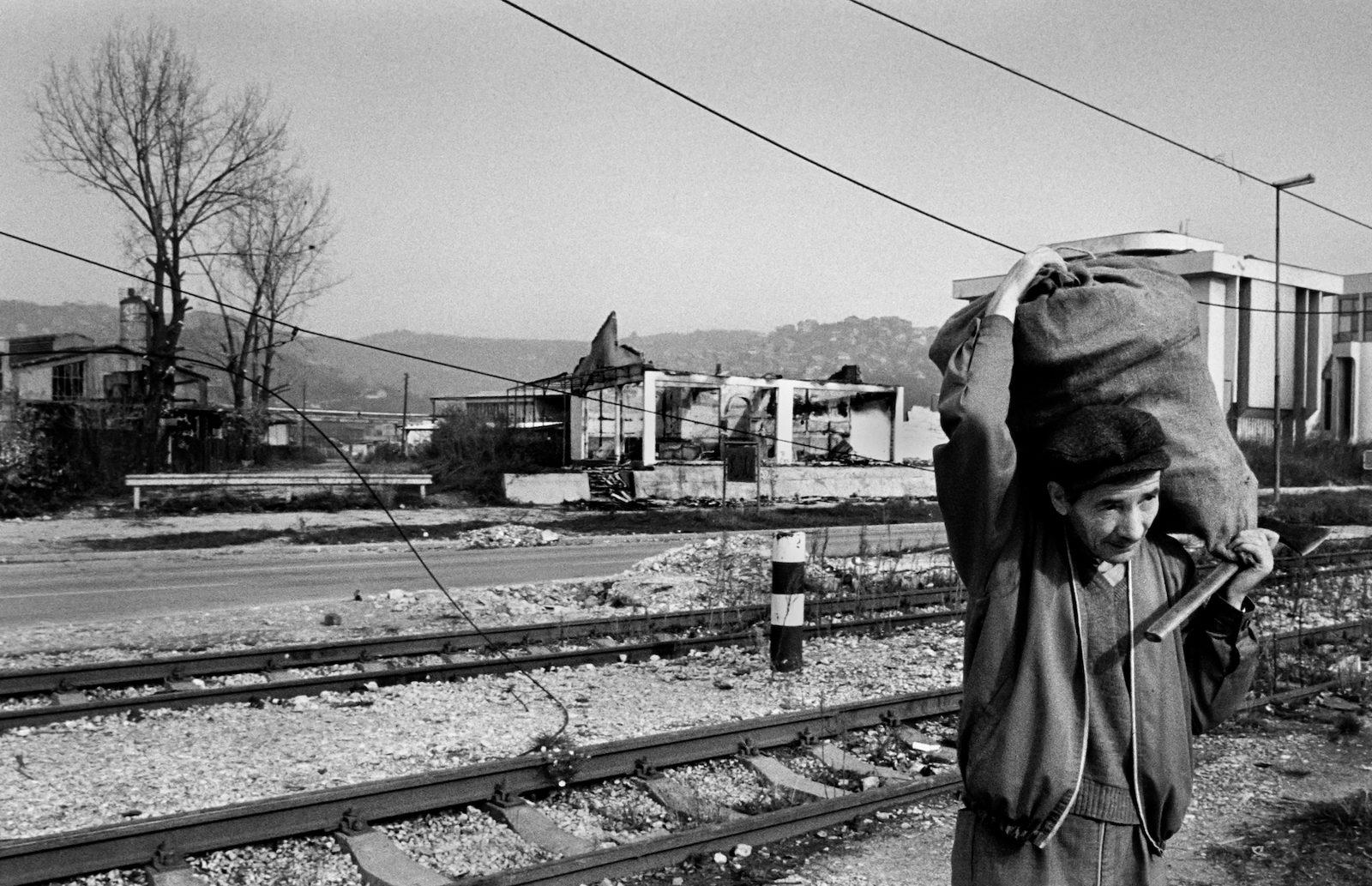 An elderly Sarajevo man carries a bag of firewood and an axe in the western part of the besieged Bosnian capital on December 3rd, 1992. Sarajevo, where temperatures drop below freezing has been without electricity, gas and running water since April 1992. The only trees left standing are in areas dangerously exposed to sniper fire.