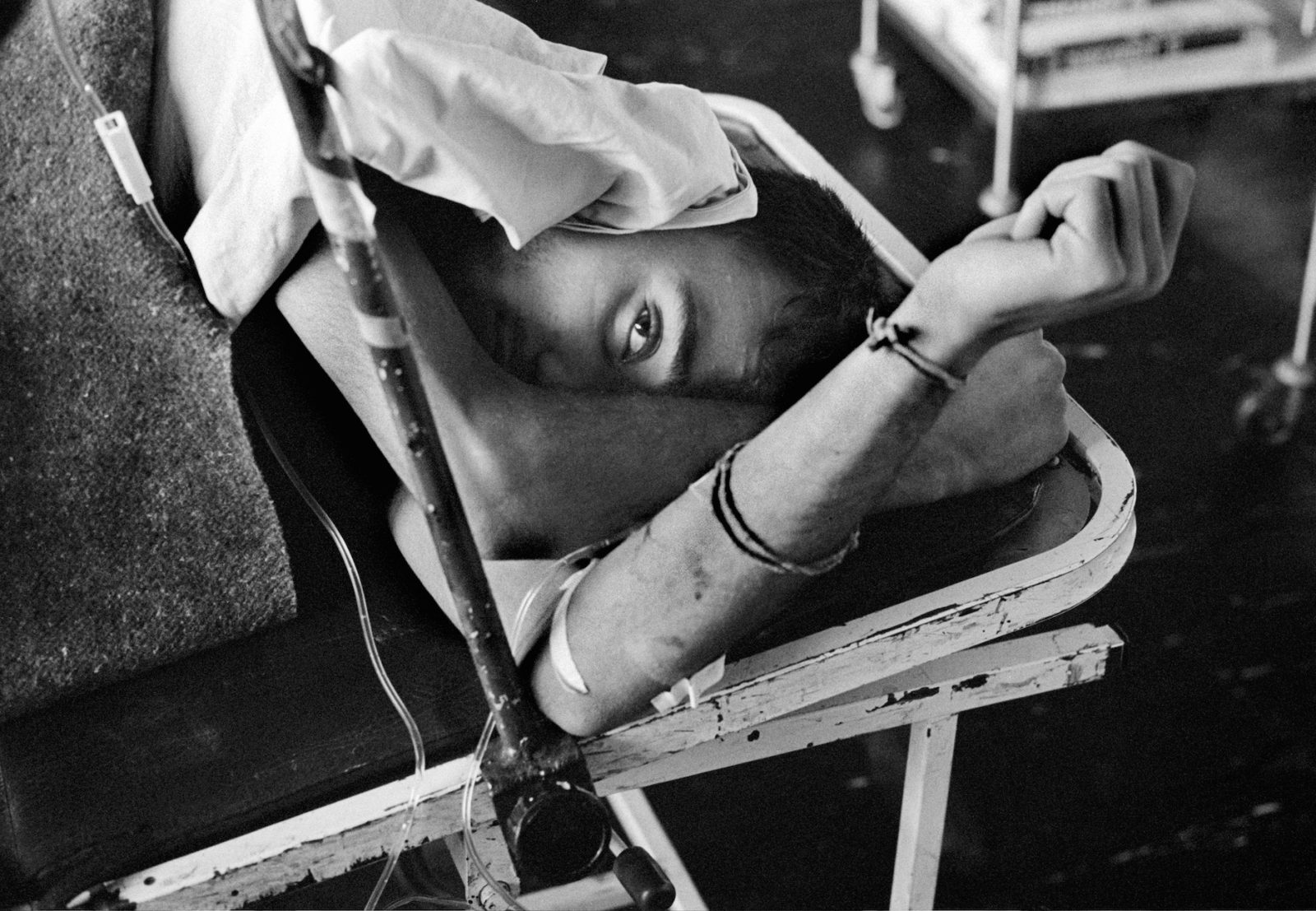 A wounded man with an intravenous drip in hospital during the siege on Sarajevo by Serb troops. Doctors and nurses working in the hospitals through the conflict operate on the injured without electricity, heating, light and drugs.