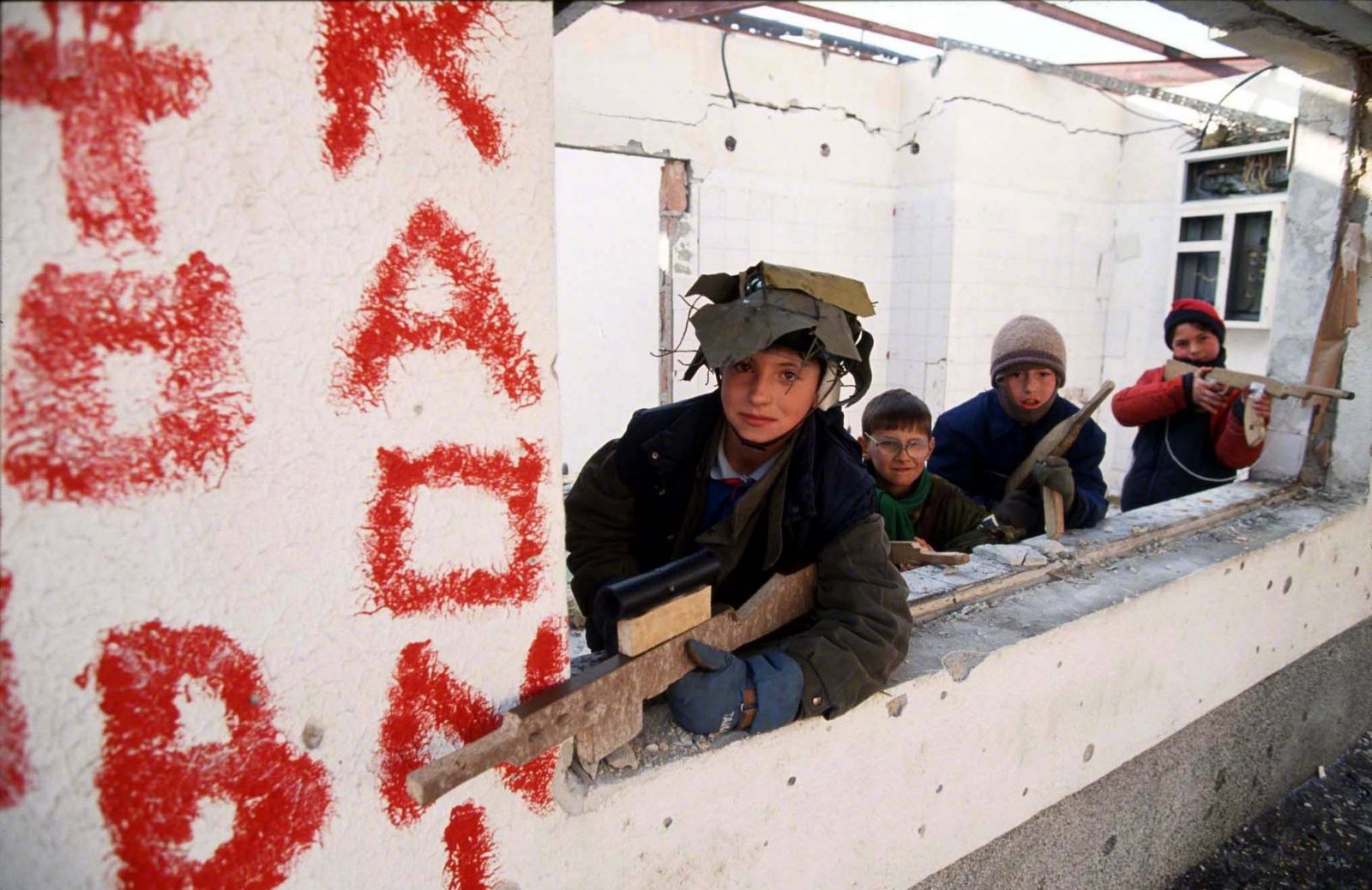 A group of children with toy weapons playing in the ruins of a destroyed building. Sarajevo, January 1993. Photo Copyright © Peter Kullmann| Zone5 | fullframeRAW