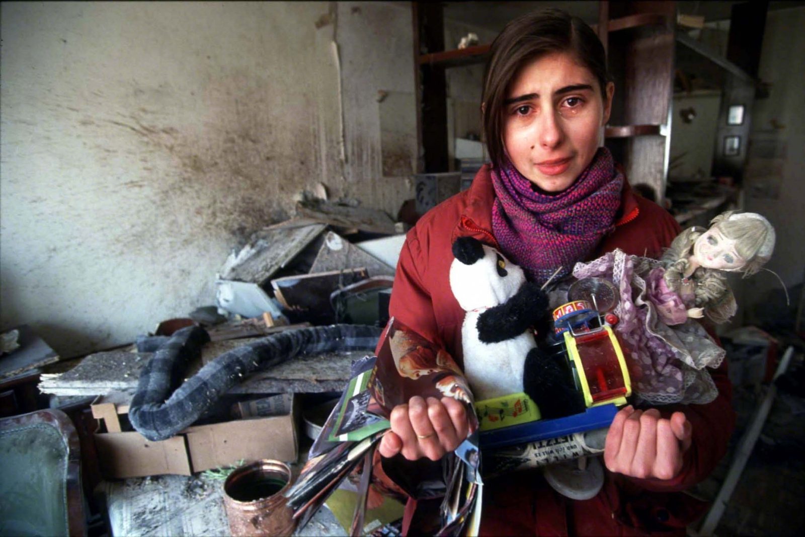 Unknown girl retrieves some toys from her destroyed home after a tank shell had hit the house without exploding. Sarajevo, Dobrinja, 1993. Photo Copyright © Peter Kullmann| Zone5 | fullframeRAW