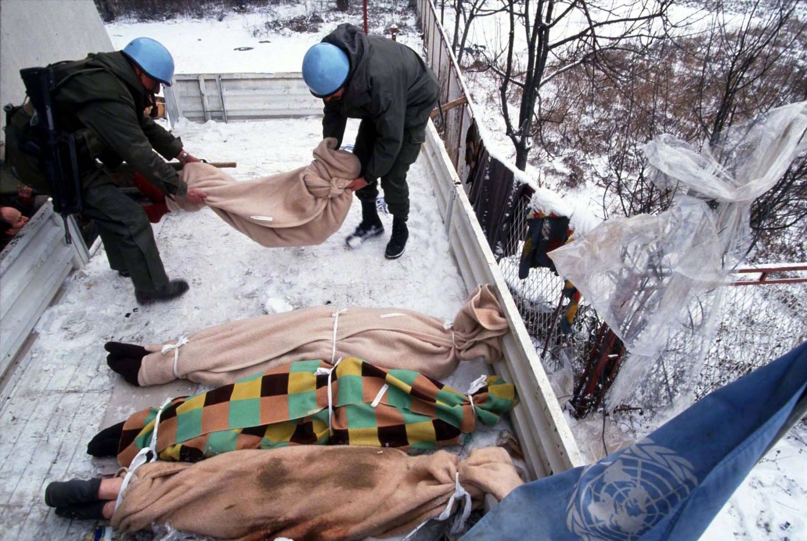 UNPROFOR soldiers placing bodies of deceased retirement home residents wrapped in blankets onto loading area of military truck. Retirement home situated next to frontline had been cut off from medical and food supplies due to fighting for several weeks. Sarajevo, Dobrinja, Decembre 1992. Photo Copyright © Peter Kullmann| Zone5 | fullframeRAW