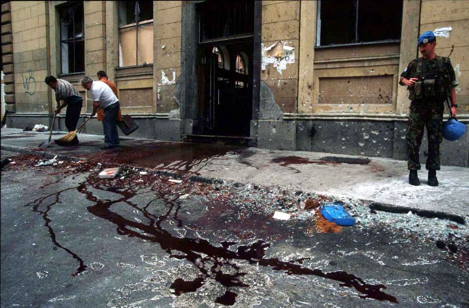 Men cleaning up street of blood after mortar shell detonation. UNPROFOR Officer looking onto the point of impact. Markale Massacre, Sarajevo, 28 August 1995. Photo Copyright © Peter Kullmann| Zone5 | fullframeRAW