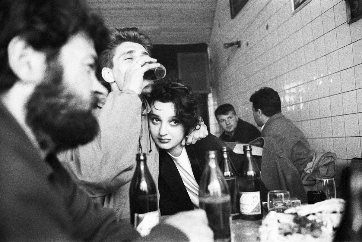 A woman sits with a group of soldiers at a cafe in Sarajevo.