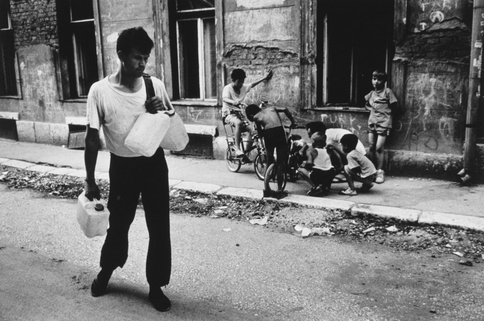 Mujo Hozbo on his 3 kilometer walk through Sarajevo to get water during the Bosnian War. Throughout 1993, the Bosnian capital of Sarajevo was a city struggling for survival. Two years of virtual siege had numbed and exhausted the population of 300,000, 15,000 of whom had been killed in the war by the end of the year. There was talk of autonomous provinces, safe havens and cease-fires, but the reality was one of bombs and bullets.