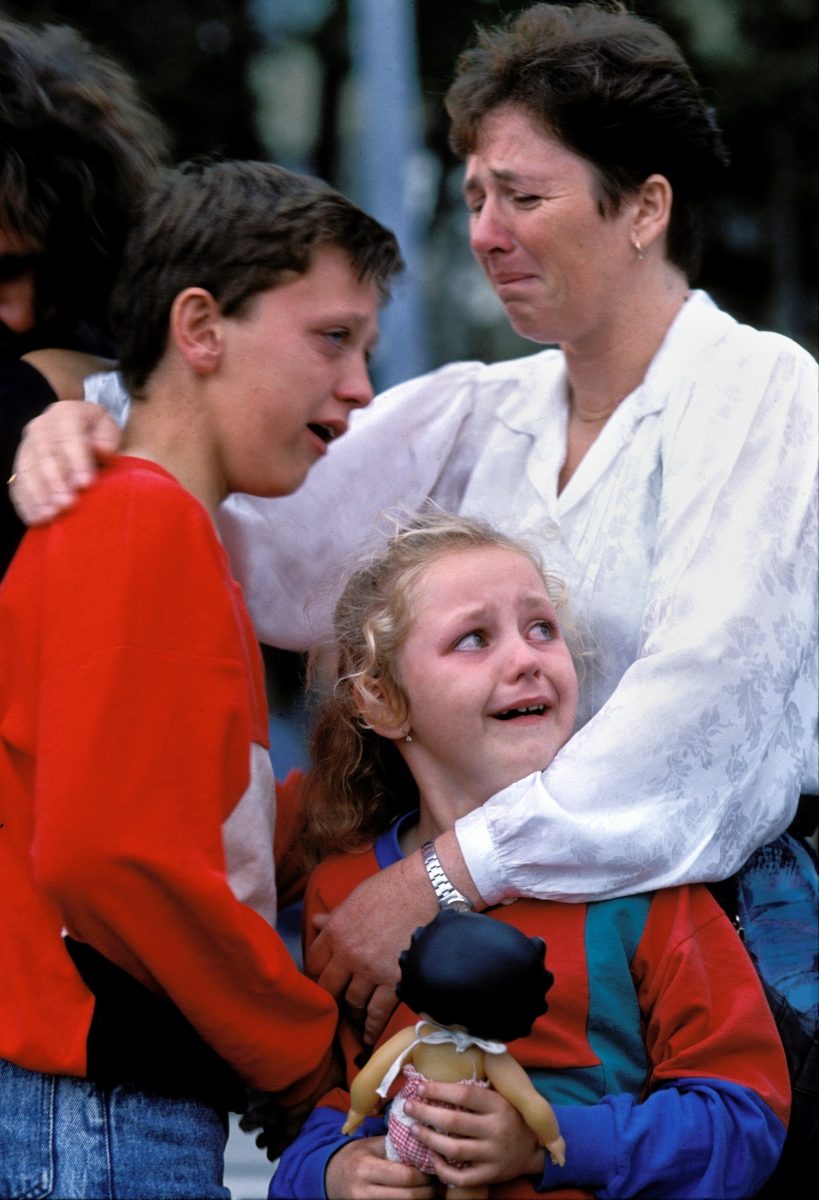 Distraught family members weep as a Red Cross bus with refugees from Sarajevo and other parts of Bosnia departs for exile in western Europe, Zagreb, Croatia 1992. An estimated 200,000 people died during the Bosnian war, and over 10,000 people in total were killed in Sarajevo during the 3-1/2 year siege.
