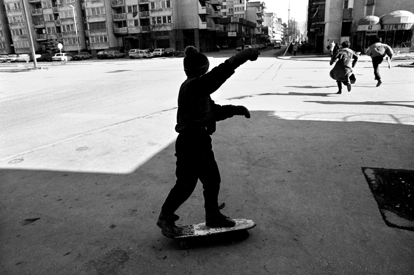 Aldin Jogic balances on his skateboard and watches as two adults race across an intersection under Serb sniper fire in Sarajevo, Bosnia-Herzegovina, February 1993.