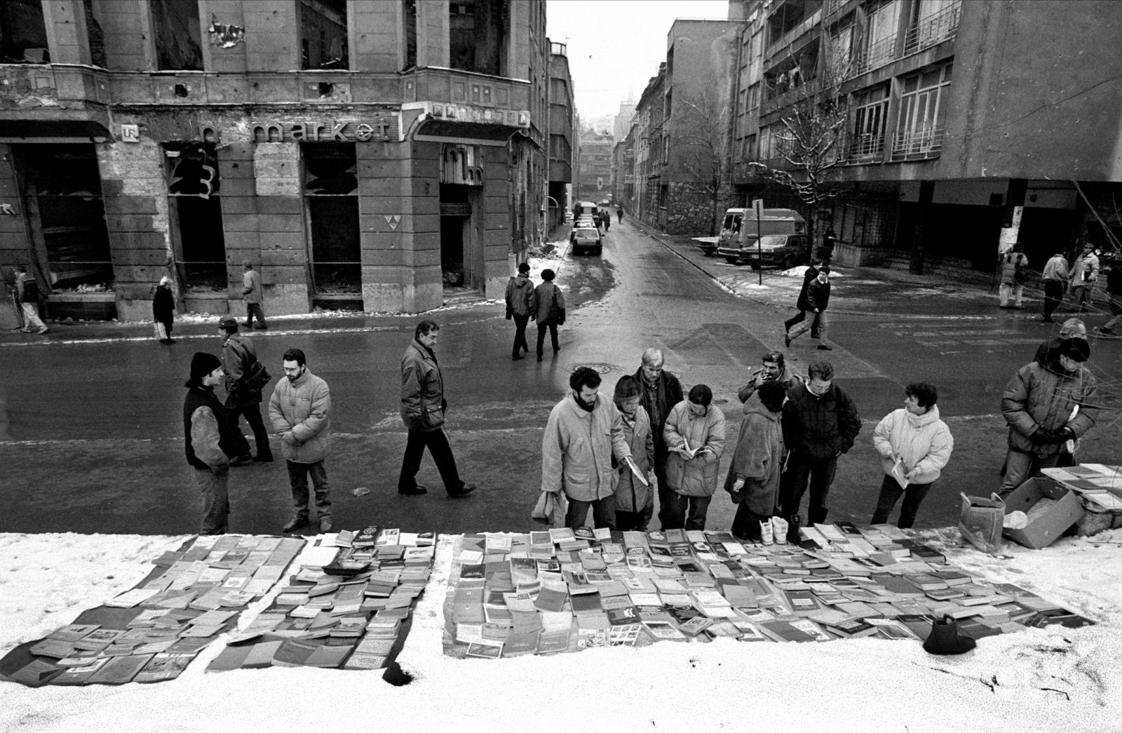 Sarajevans browse among books for sale spread out on a tarp laid over the snow during the final days of the siege of the city, Sarajevo, Bosnia and Herzegovina, February 1996.