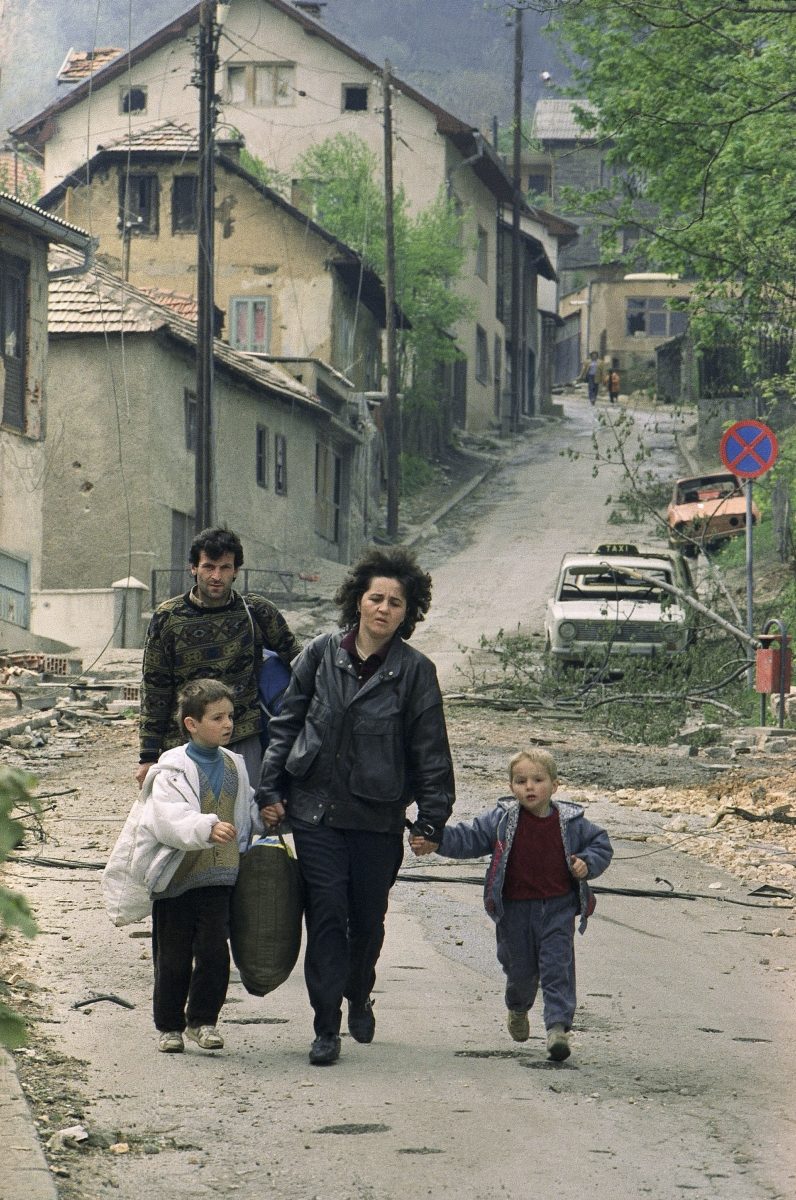 Hustling her children down the road, a family leaves their home on a hillside, May 8, 1992 in Sarajevo.