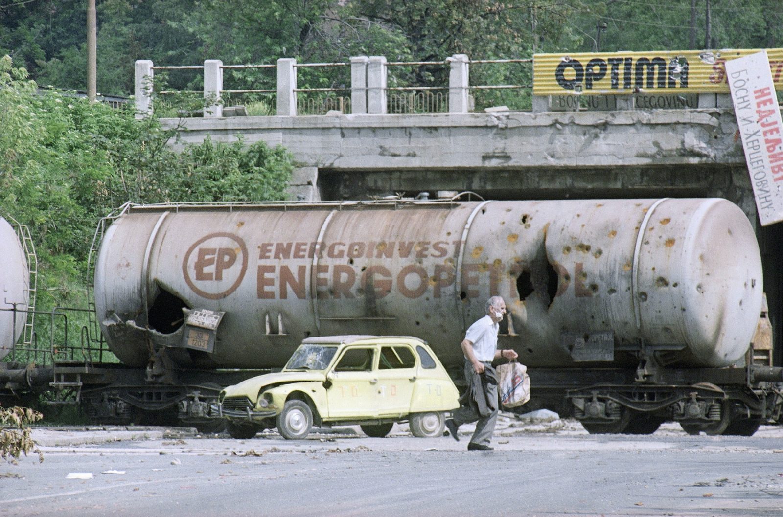 A man walks past vehicles destroyed in recent fighting in Sarajevo, June 20, 1992. Residents of the Bosnian capital, under siege for over two months, are desperately in need of food and medicine.