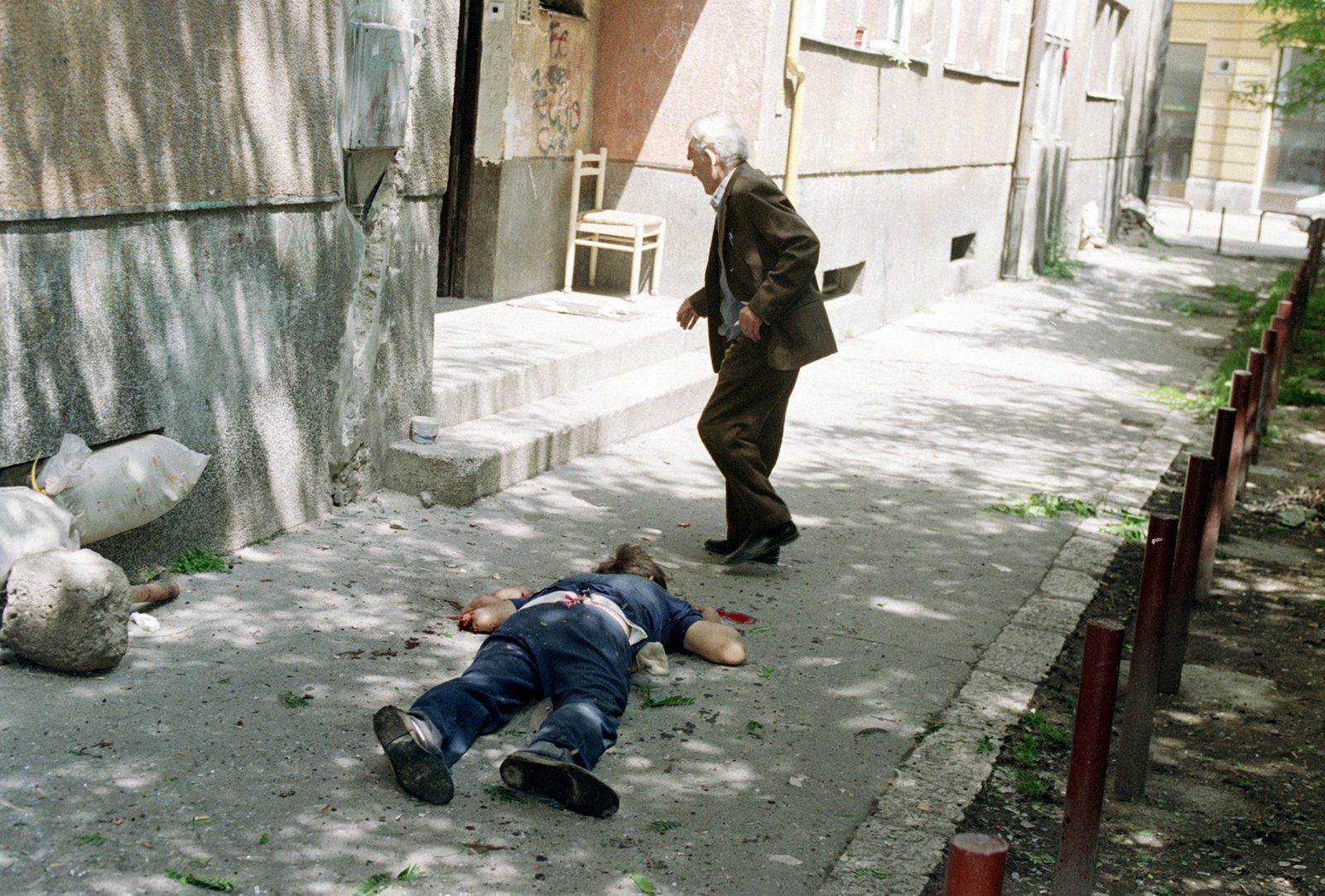 A man runs for cover past a dead civilian during heavy shelling which killed at least seven people and wounded dozens in central Sarajevo, Bosnia and Herzegovina, Monday, June 1992. Serb fighters battled Bosnian defenders with artillery, mortars and machine guns, frustrating efforts to start airlifting food to residents threatened by starvation.