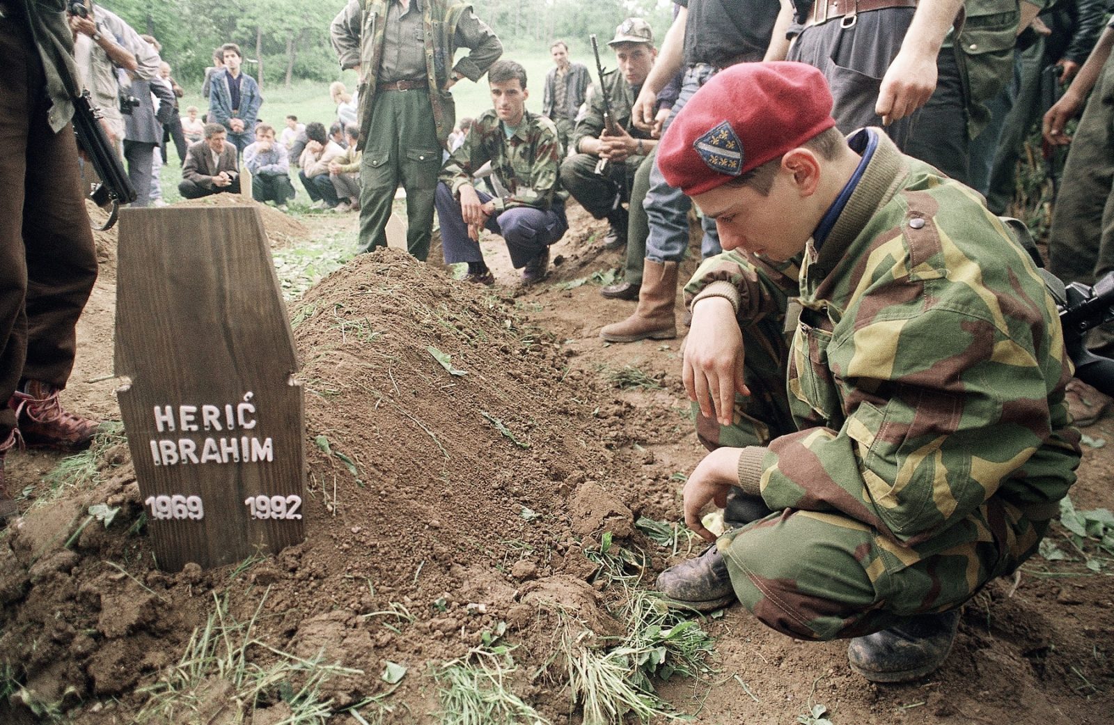 A young Bosnian soldier kneels by the grave of his friend Heric Ibrahim, on Tuesday, June 9, 1992 in Sarajevo who was killed in combat against Serbian forces yesterday. After a relatively quiet night, sporadic booms of heavy weapons and anti-aircraft gun volleys could be heard at a distance in Sarajevo Tuesday, contrasting with Monday when 20 shells a minute rained on the city.