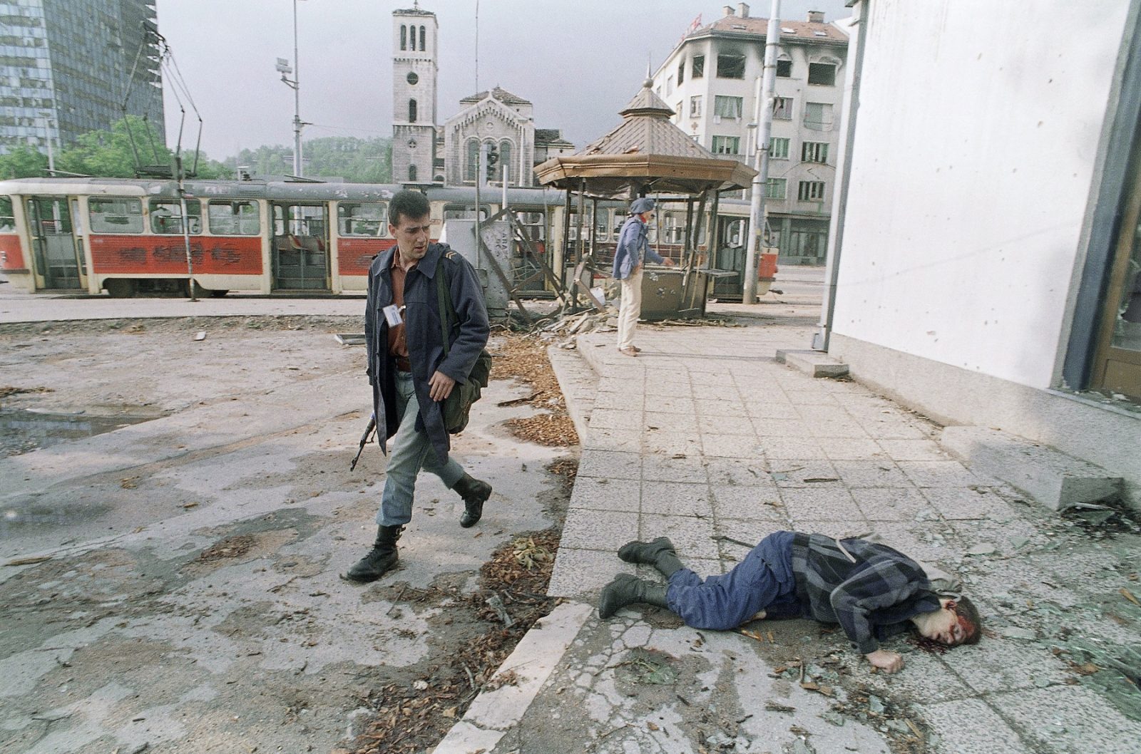 A Bosnian looks back at the body of a young man killed by a sniper hours after a cease-fire went into effect, Monday, June 15, 1992 in Sarajevo. The man, an off-duty soldier, was killed as he walked home Monday morning along an exposed stretch of road.