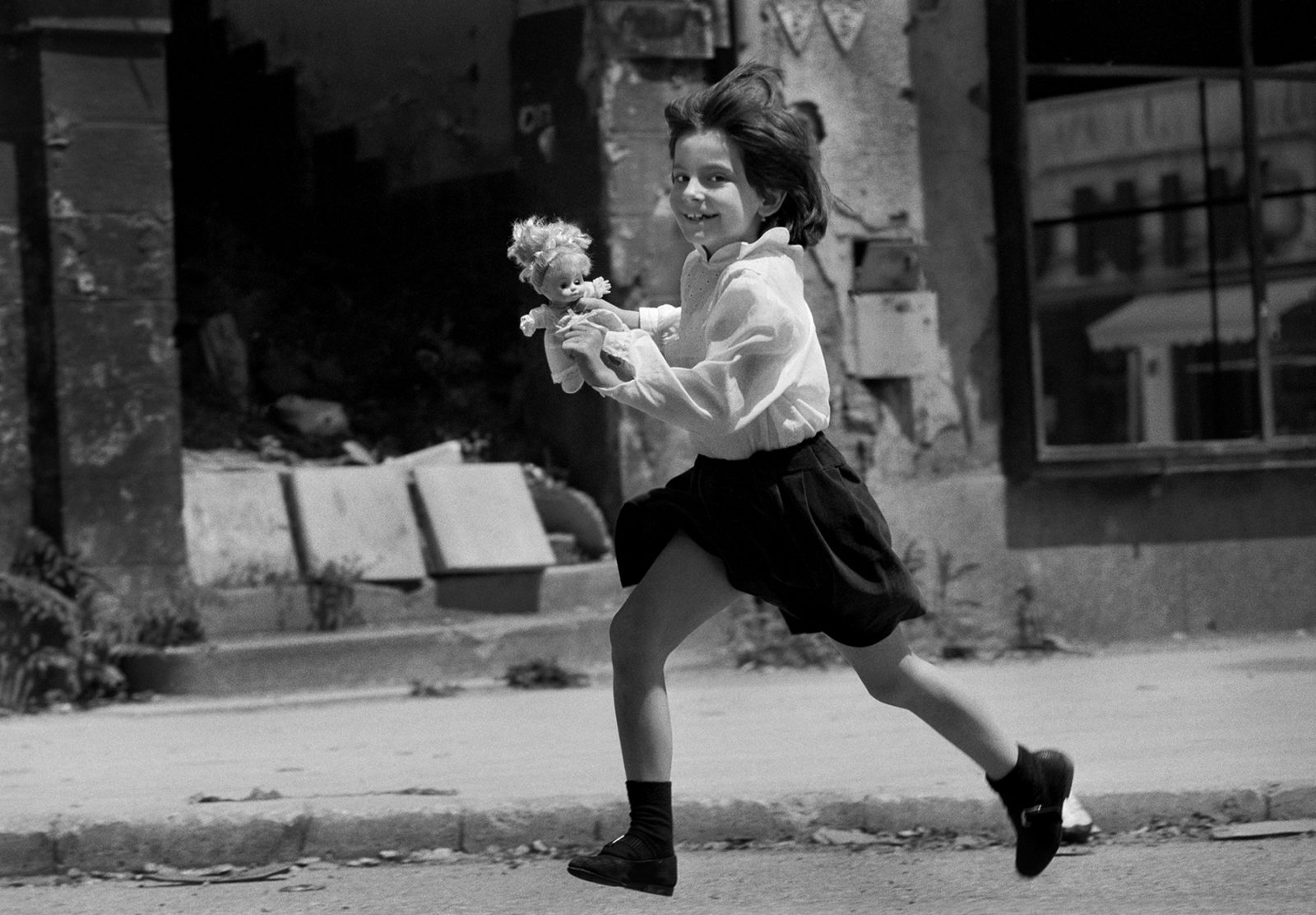 A smiling child runs across 'Sniper Alley' in Sarajevo during heavy fighting in 1993. (Photo By Tom Stoddart/Getty Images)