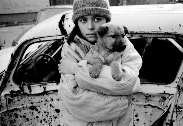 SARAJEVO, BOSNIA - AUGUST 1992: A Dog, Man's Best Friend - He is your friend, your partner, your defender, your dog. You are his life, his love, his leader. He will be yours, faithful and true, to the last beat of his heart. You owe it to him to be worthy of such devotion. A child and puppy in the shattered landscape of Sarajevo. The girl in this picture was identified after the war as Merima Jakupovic with her puppy Smoki. (Photo by Tom Stoddart/Reportage by Getty Images)