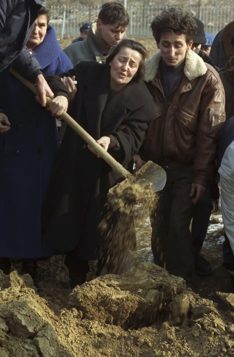 A grieving widow hurriedly spreads soil over the coffin of her late husband in the sporting grounds in the capital Sarajevo. The dead are victims from numerous Serbian attacks from the mountains surrounding the city under siege.Snipers and mortar bombardments claim lives every day and even the makeshift cemeteries are not safe as mourners are attacked as they bury their loved ones. Sarajevo 1993