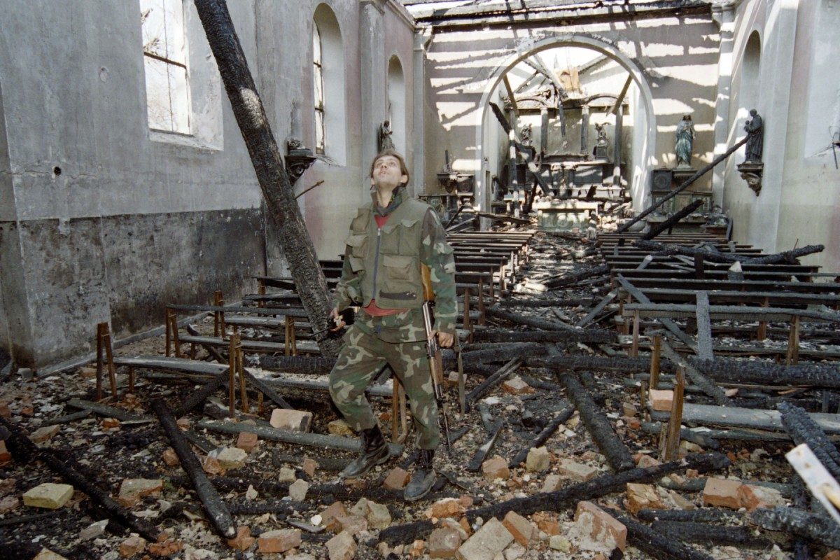A Bosnian soldier surveys the destroyed church in Stup on March 23, 1993. Stup, Sarajevo.